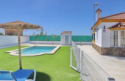 a backyard with a pool and an umbrella and grass at Alojamiento Rural Las Quintas in Conil de la Frontera