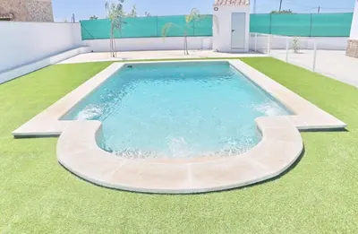 a swimming pool on top of a green lawn at Alojamiento Rural Las Quintas in Conil de la Frontera