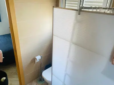 a bathroom with a toilet and a shower door at Villa Eterno in Chiclana de la Frontera
