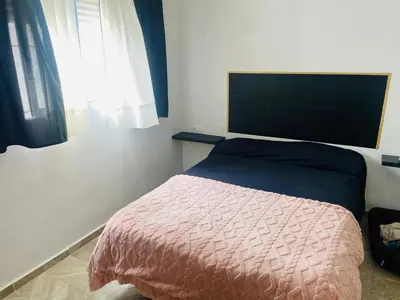 a bedroom with a bed with a pink blanket and a window at Villa Eterno in Chiclana de la Frontera