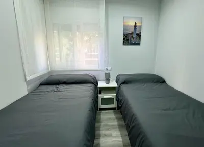 a bedroom with two beds and a table and a window at El Corner de Esquivel Grupo AC Gestion in Cádiz