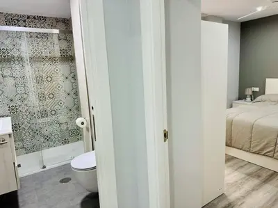 a bathroom with a shower and a toilet and a bed at El Corner de Esquivel Grupo AC Gestion in Cádiz