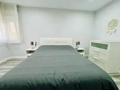 a white bedroom with a large bed and two dressers at El Corner de Esquivel Grupo AC Gestion in Cádiz