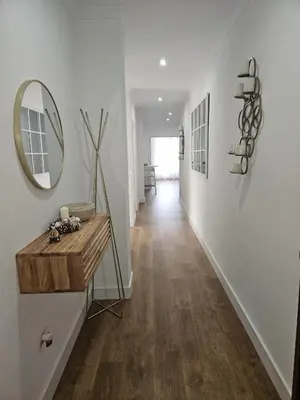 a hallway with white walls and a mirror and wood floors at Precioso Ático de Lujo en Calle Ancha in Sanlúcar de Barrameda