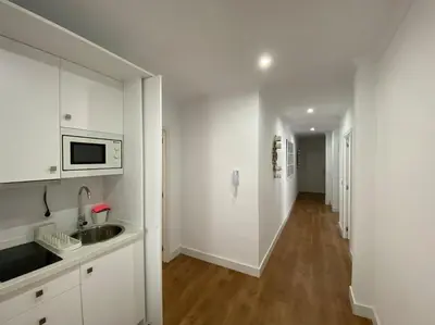 a kitchen with white cabinets and a sink and a hallway at Precioso Ático de Lujo en Calle Ancha in Sanlúcar de Barrameda