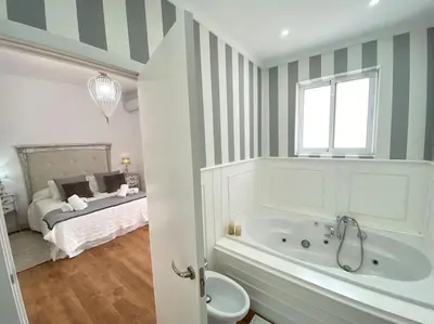 a bathroom with a tub and a bed in the background at Precioso Ático de Lujo en Calle Ancha in Sanlúcar de Barrameda