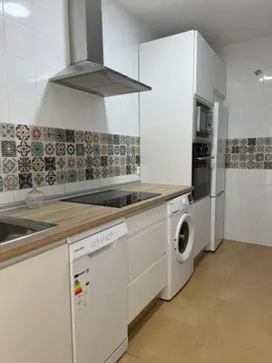 a kitchen with a stove top oven next to a washing machine at Piso Centro Chiclana in Chiclana de la Frontera