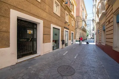 a person walking a dog down a street at Kotinousa Cádiz - Centro historico in Cádiz