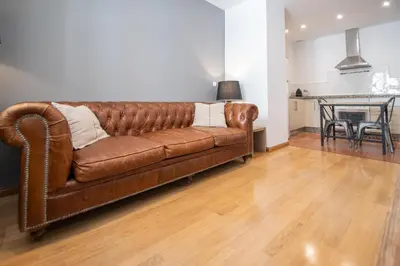 a brown leather couch in a living room with a table at Kotinousa Cádiz - Centro historico in Cádiz