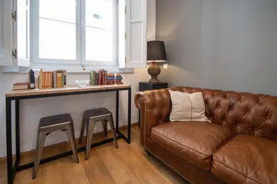 a living room with a brown couch and a table at Kotinousa Cádiz - Centro historico in Cádiz