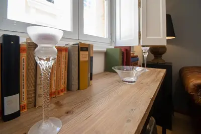 a wooden table with a glass vase and books at Kotinousa Cádiz - Centro historico in Cádiz