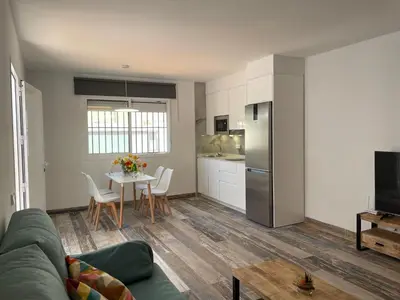 a living room with a couch and a table and a kitchen at Casita Kairós in Conil de la Frontera