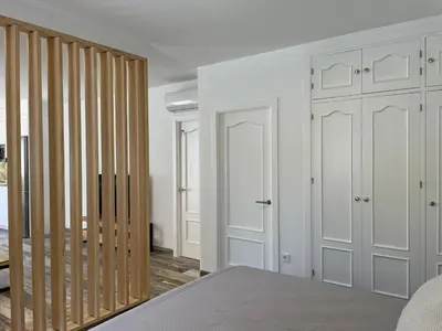 a bedroom with white walls and wooden closet doors at Casita Kairós in Conil de la Frontera
