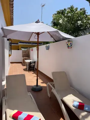 a patio with two chairs and an umbrella at Casita Kairós in Conil de la Frontera