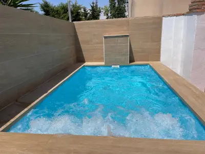a large swimming pool with a concrete wall at Casita Kairós in Conil de la Frontera