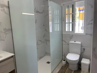 a bathroom with a toilet and a glass shower at Casita Kairós in Conil de la Frontera