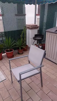 a white chair sitting on a patio with plants at Duplex convento la victoria in Sanlúcar de Barrameda