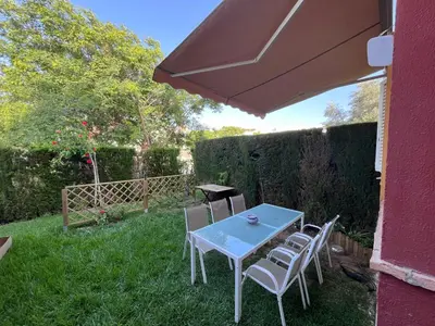 a table and chairs under an umbrella in the yard at Adosado con jardín Urb Galia Ballena in Cádiz