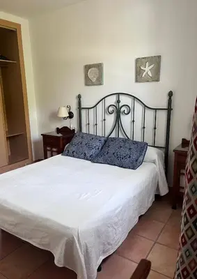 a bedroom with a large bed with white sheets at Adosado con jardín Urb Galia Ballena in Cádiz