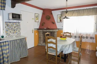 a kitchen and dining room with a table and a fireplace at Chalet Enol Sol in Chiclana de la Frontera