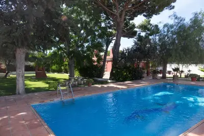 a blue swimming pool with trees in the background at Chalet Enol Sol in Chiclana de la Frontera