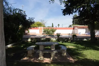 a stone bench in a yard with a table at Chalet Enol Sol in Chiclana de la Frontera