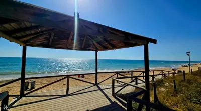 a view of the beach from a wooden boardwalk at Chipiona - Playa a 200m terraza piscina padel in Chipiona