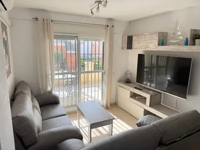 a living room with a couch and a flat screen tv at Chipiona - Playa a 200m terraza piscina padel in Chipiona