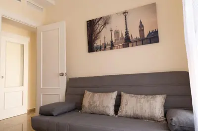 a couch in a living room with a picture on the wall at El Ático del Olivarillo in San Fernando