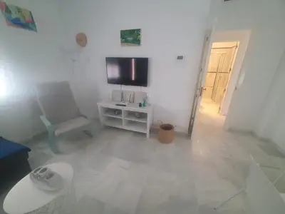a white living room with a chair and a television at Larga 109 in El Puerto de Santa María