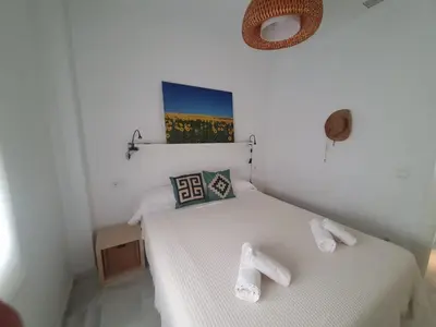 a white bedroom with a bed with towels on it at Larga 109 in El Puerto de Santa María