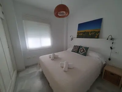 a bedroom with a white bed with two crosses on it at Larga 109 in El Puerto de Santa María