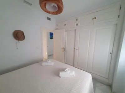 a white bedroom with two towels on a bed at Larga 109 in El Puerto de Santa María