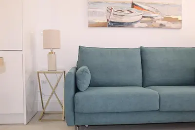 a blue couch in a living room with a painting at Apartamento Infantas 26 in Sanlúcar de Barrameda