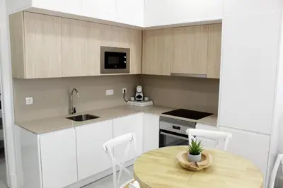 a kitchen with white cabinets and a wooden table at Apartamento Infantas 26 in Sanlúcar de Barrameda