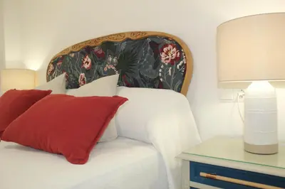 a bedroom with a bed with a red pillow and a table at Apartamento Infantas 26 in Sanlúcar de Barrameda