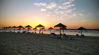 a group of beach chairs and umbrellas on a beach at Apartamento Infantas 26 in Sanlúcar de Barrameda