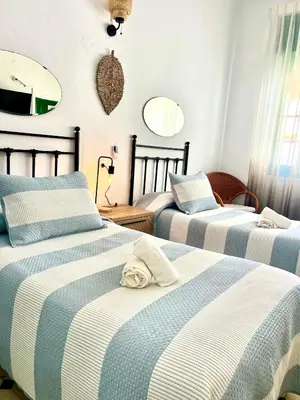 a bedroom with a large bed with a green window at Hostal El Faro in Chipiona