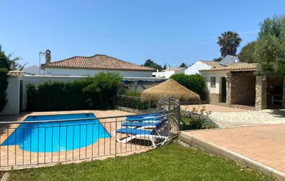 a swimming pool with two chairs next to a house at Casa Juan in Conil de la Frontera