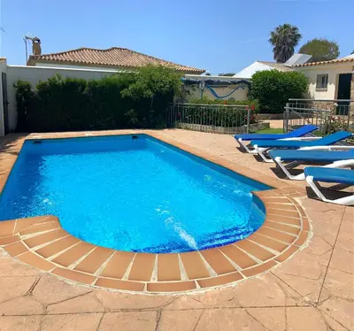 a large swimming pool with lounge chairs in a yard at Casa Juan in Conil de la Frontera