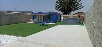 a small yard with a blue shed and a lawn at Casita de madera Azul in Chiclana de la Frontera
