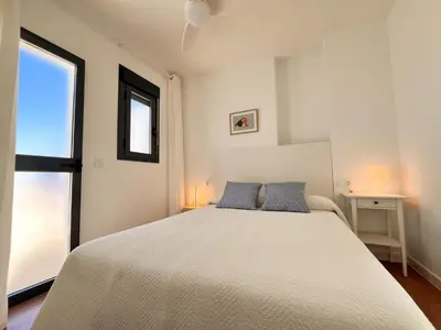 a bedroom with a large white bed and a window at Ático Castillo by Summerland Rota in Rota