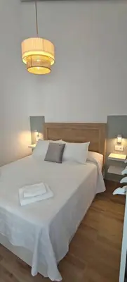 a bedroom with a white bed and a chandelier at Los Jereles. in Jerez de la Frontera