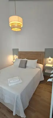 a bedroom with a large white bed and a chandelier at Los Jereles. in Jerez de la Frontera