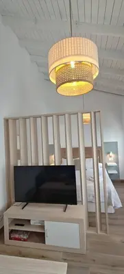 a living room with a television and a chandelier at Los Jereles. in Jerez de la Frontera