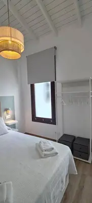 a bedroom with a white bed and a window at Los Jereles. in Jerez de la Frontera