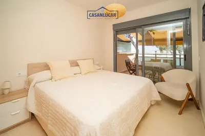 a bedroom with a large white bed and a chair at Apartamento Soto Verde in Sanlúcar de Barrameda