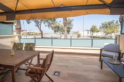 a patio with a table and chairs and a view of the ocean at Apartamento Soto Verde in Sanlúcar de Barrameda