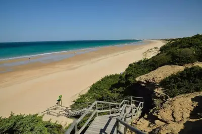 a staircase leading to a beach next to the ocean at Dúplex Chiclana Centro con Terraza y Parking By Chiclana Dreams in Chiclana de la Frontera