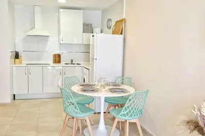a kitchen with a table and chairs and a refrigerator at Dúplex Chiclana Centro con Terraza y Parking By Chiclana Dreams in Chiclana de la Frontera